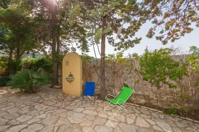 two chairs and a surfboard next to a fence at Villino Dei Gabbiani in Castellammare del Golfo