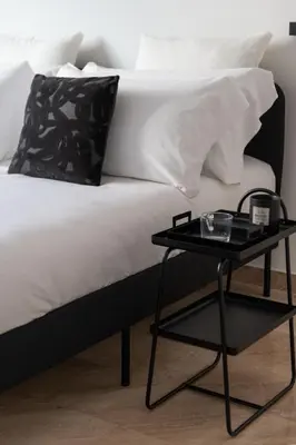 a bed with a black side table next to it at Ruggero City View apartment by Wonderful Italy in Palermo