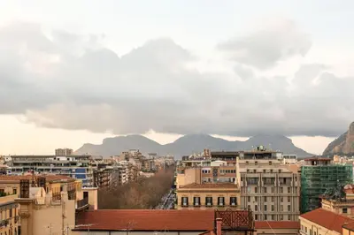 a city with buildings and mountains in the background at Ruggero City View apartment by Wonderful Italy in Palermo