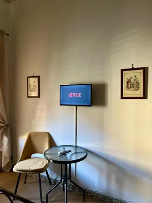 a tv on a wall with a table and chairs at Leon in Palermo
