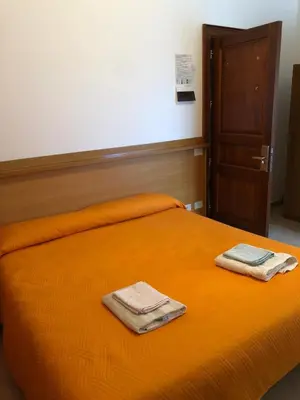 an orange bed with two towels on top of it at Albergo BELVEDERE in Santa Cristina Gela