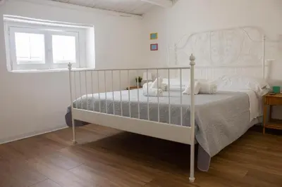 a white bed in a white bedroom with a window at Eli's Home in Terrasini