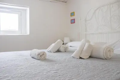 a white bedroom with a white bed with towels on it at Eli's Home in Terrasini