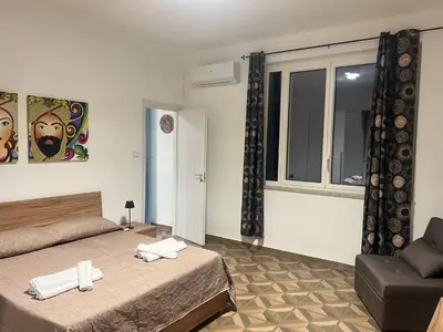 a bedroom with two beds and a chair and a window at Trinacria in Capaci