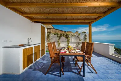 a table and chairs on a balcony with the ocean at Terrazza BluOltremare, Castellammare del Golfo in Castellammare del Golfo