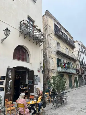 two people sitting at a table outside of a building at Nel Vicoletto House in Palermo