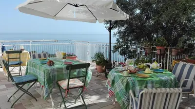 a table and chairs with a table and an umbrella at B&B Talìa in Scopello