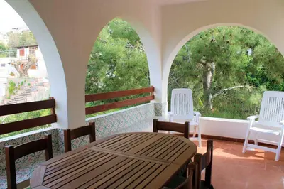 a porch with two arched windows and a wooden table and chairs at I Cinque Archi Apartment in Alcamo