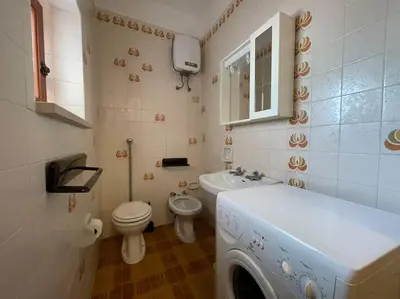 a bathroom with a toilet sink and a washing machine at I Cinque Archi Apartment in Alcamo