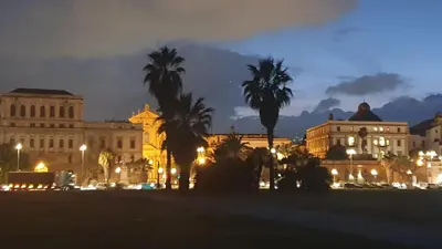 a city at night with palm trees and buildings at Note di Palermo Loft in Palermo