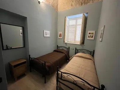 two beds in a room with a mirror and a window at Donna Maria in Cinisi