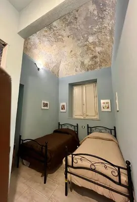 two beds in a room with a painting on the ceiling at Donna Maria in Cinisi