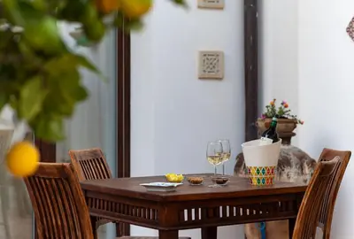 a wooden table with two chairs and a glass of wine at Le Margherite in San Vito lo Capo