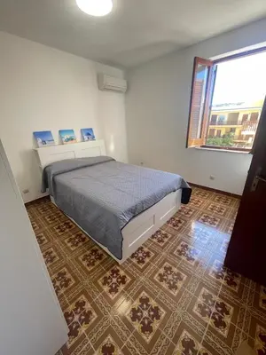 a bedroom with a bed and a large window at nanzi u mare in San Vito lo Capo