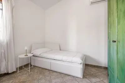 a white bed in a room with a side table at Villa Zagara Swimming Pool and Seaview in Ficarazzi