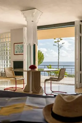 a room with a table and chairs and a view of the ocean at villa Capo Zafferano in Bagheria