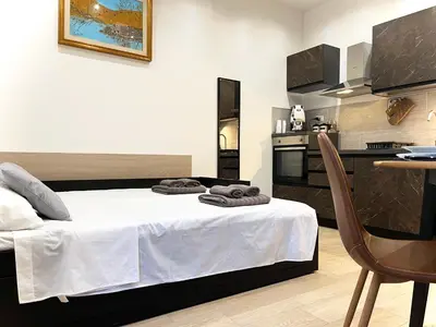 a bedroom with a bed and a table and a kitchen at SILVIO'S Apartment in Castellammare del Golfo