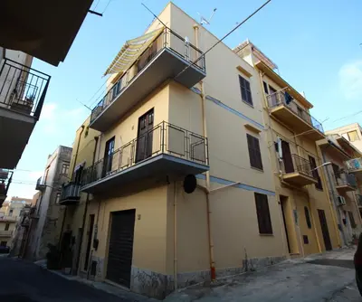 a yellow building with a balcony on a street at Bovio guest House in Castellammare del Golfo