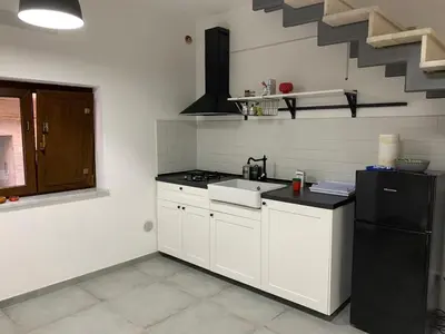 a kitchen with white cabinets and a black refrigerator at Dai Mori in Lascari
