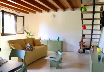 a living room with a couch and a person sitting on a stairs at Casale Morillo in Campofelice di Roccella