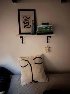 a pillow on a bed with a shelf on the wall at Casteldaccia Stay, mieszkanko Kingi in Casteldaccia