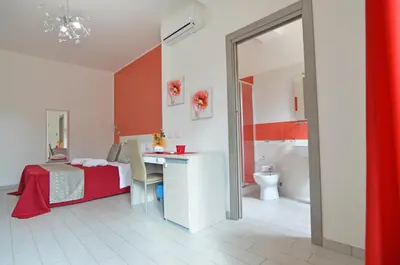 a bedroom with a bed and a desk and a bathroom at Le Falesie di Castelluzzo in Castelluzzo