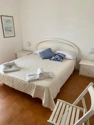 a bedroom with a bed with towels and a chair at Scopello Beach in Scopello