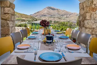 a long table with blue and orange plates and glasses at VILLA AGLEA Luxury By Sicily Home Solutions in Castellammare del Golfo