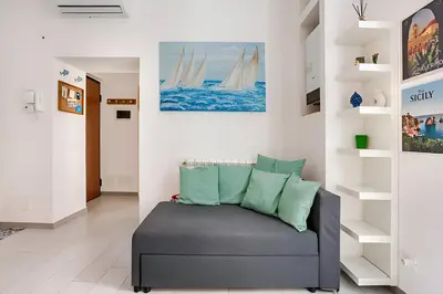 a living room with a gray couch with green pillows at Casa Bellini in Palermo