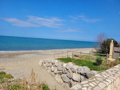 a beach with a stone wall and the ocean at La Perla Di Campofelice in Campofelice di Roccella