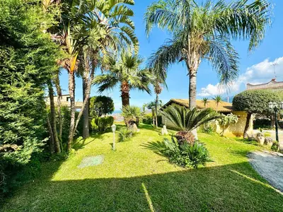 a garden with palm trees and a house at Villa Bellavista in Carini