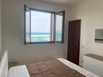 a bedroom with a bed and a window with the ocean at Baia Marina Oasi in Balestrate