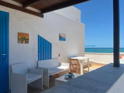 a patio with chairs and a table on the beach at Baia Marina Oasi in Balestrate