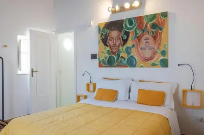 a bedroom with a bed with a painting on the wall at GuestHost - Casetta del Romito - Lovely Studios in Palermo