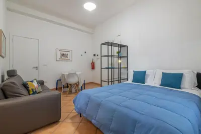 a bedroom with a large blue bed and a couch at GuestHost - Casetta del Romito - Lovely Studios in Palermo
