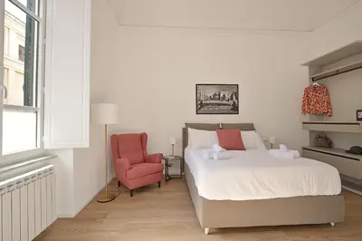 a bedroom with a bed and a pink chair at Palazzo Gregorietti Boutique Apartments in Palermo
