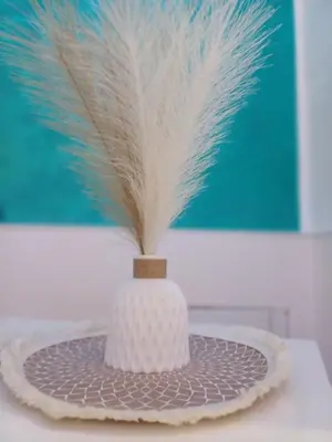 a white vase with a feather on a plate at Carruzzata 2 in Bagheria