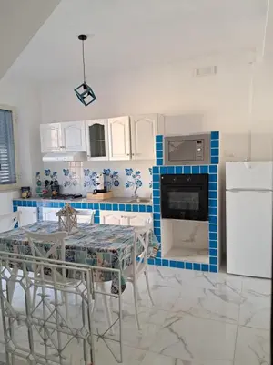a kitchen with white cabinets and blue and white appliances at House victor in Palermo