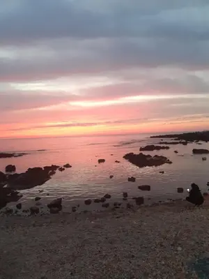 a sunset over the ocean with rocks in the water at House victor in Palermo