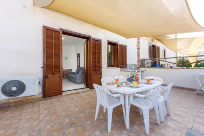 a patio with a table and chairs and an umbrella at Trilocale 4 moderno con patio a San Vito Lo Capo in San Vito lo Capo
