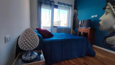 a blue bedroom with a bed and a window at utveggio view apartment in Palermo