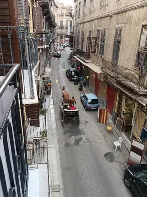 a horse pulling a cart down a city street at Calderai 52 Apartments in Palermo