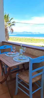 a table with wine glasses and a view of the beach at Arancina Abbronzata in Balestrate