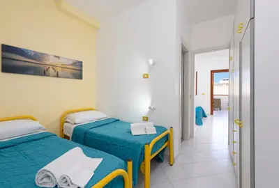 a room with two beds and a hallway at Bilocale Piano Terra a 400 mt dal mare in San Vito lo Capo