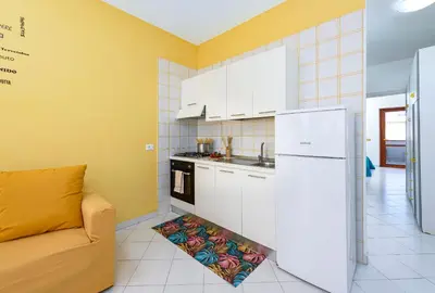 a kitchen with a couch and a white refrigerator at Bilocale Piano Terra a 400 mt dal mare in San Vito lo Capo