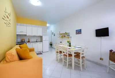 a living room with a couch and a table and a kitchen at Bilocale Piano Terra a 400 mt dal mare in San Vito lo Capo