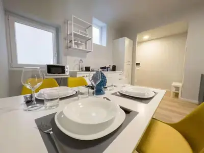 a table with plates and wine glasses and yellow chairs at Casa Calucca Barrilaio in Palermo