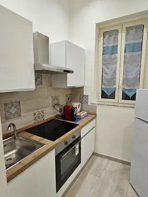 a kitchen with white cabinets and a sink and a window at Casa Amato appartamento alla zisa in Palermo