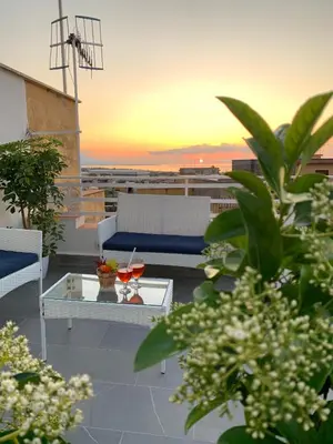 a balcony with a table and chairs and a sunset at Idea di Mare in Capaci