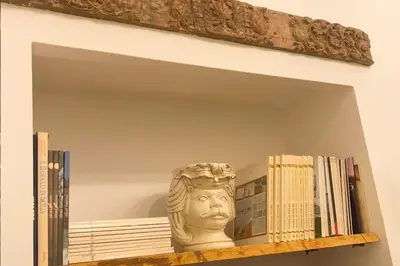 a shelf with books and a statue on it at AthaHome Deluxe in Palermo